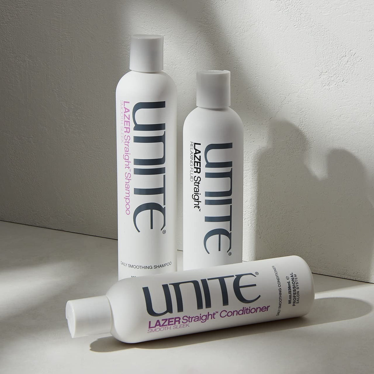 UNITE Hair LAZER Straight Relaxing Fluid anti-frizz smoothing cream applied to hair for sleek, straight styles.