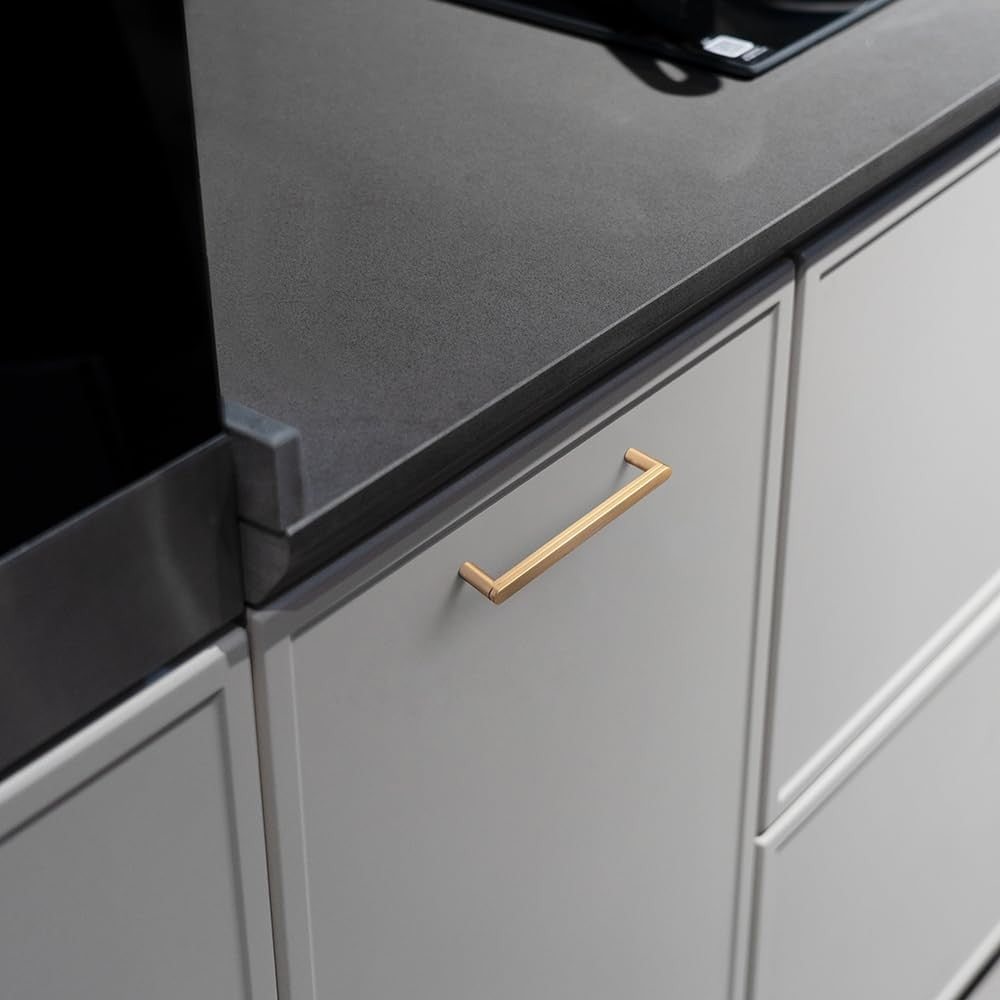 Goo-Ki 6-pack champagne bronze 5-inch grooved cabinet pull handles mounted on a cabinet door.