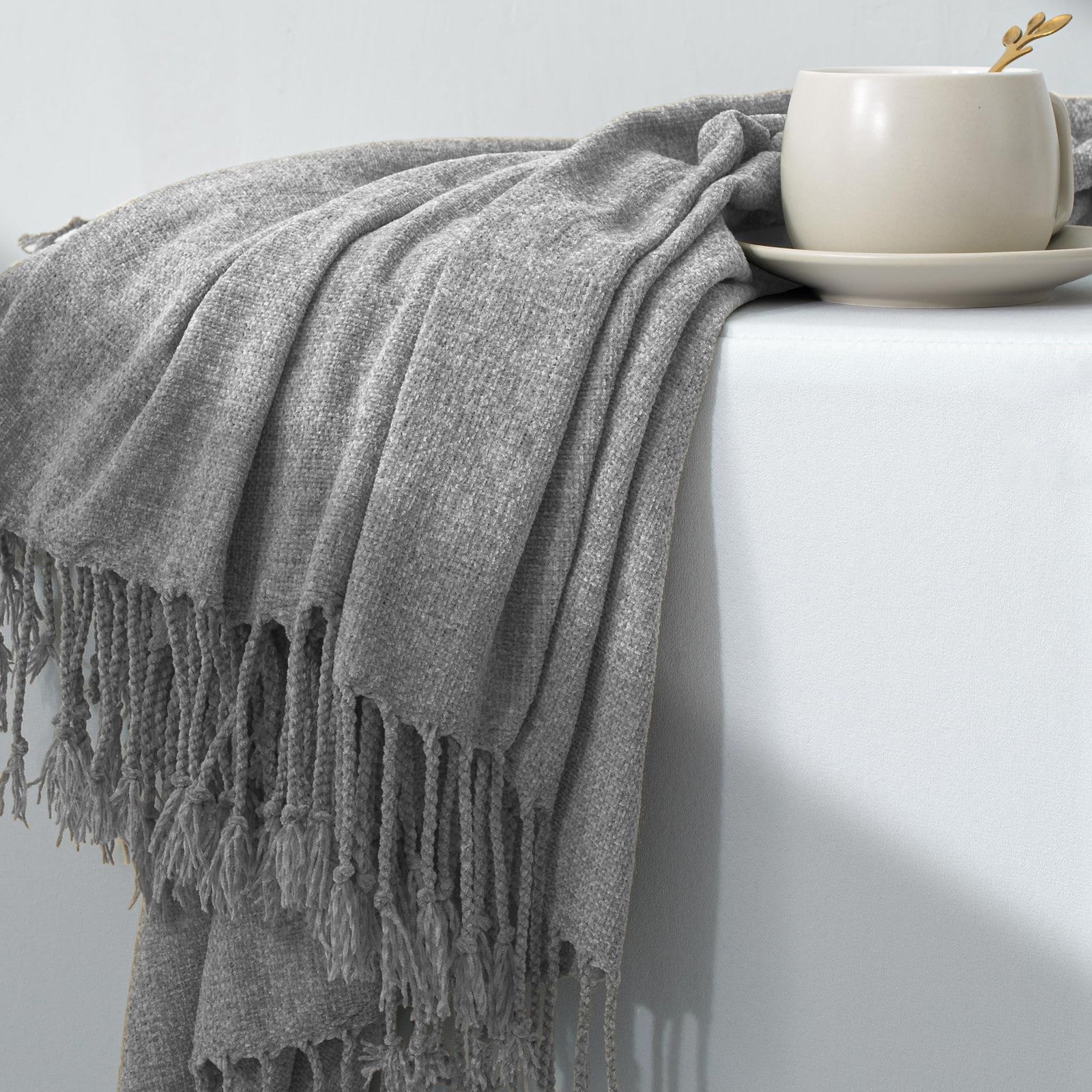 GINAMUSE chenille throw blanket with tassels draped over a sofa, soft and lightweight 60x88 inch cozy home decor accessory.