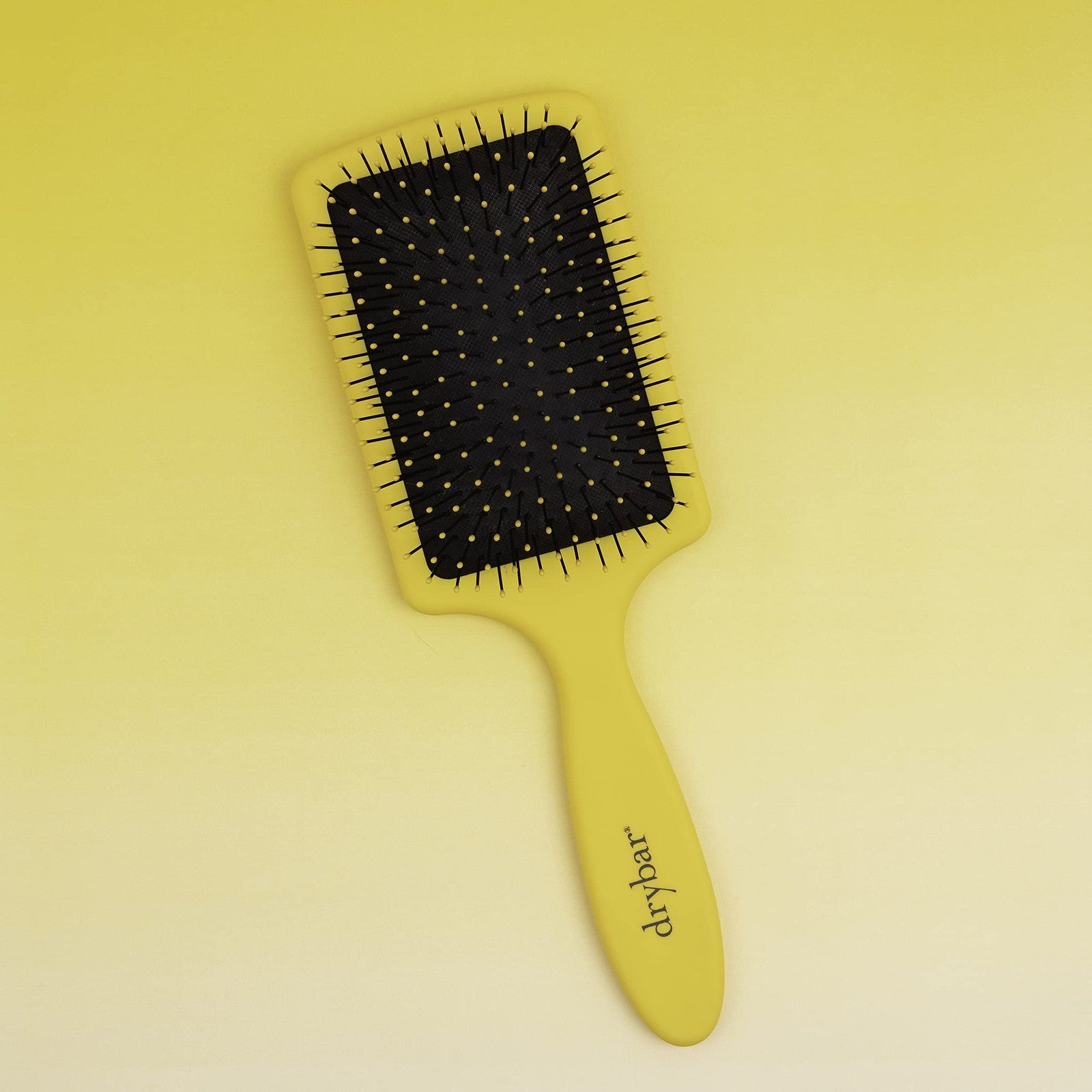 Drybar The Lemon Bar paddle brush with yellow handle and bristles, designed for detangling and styling hair.