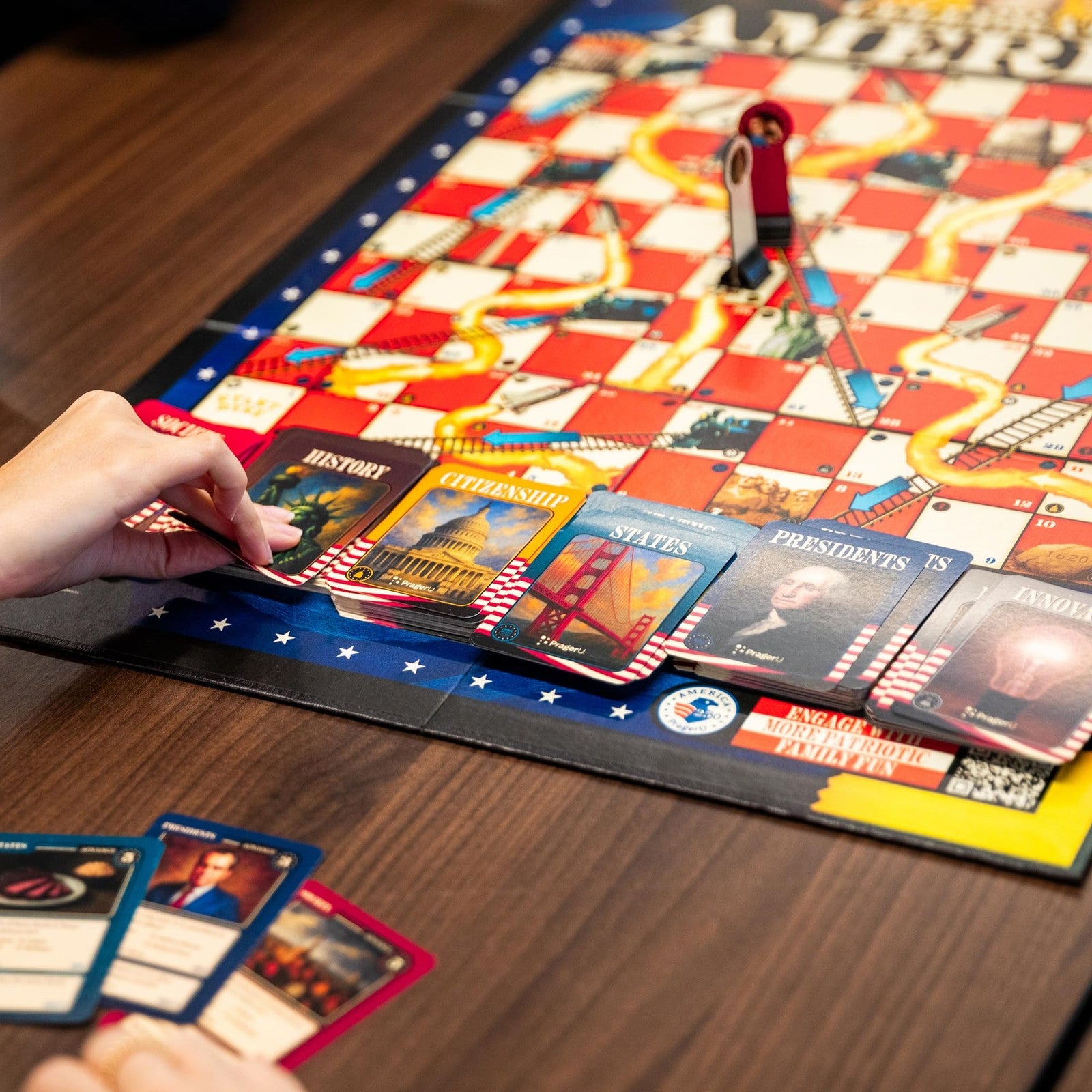 PragerU Celebrate America Race to The White House board game with USA trivia questions and game pieces on a wooden surface.