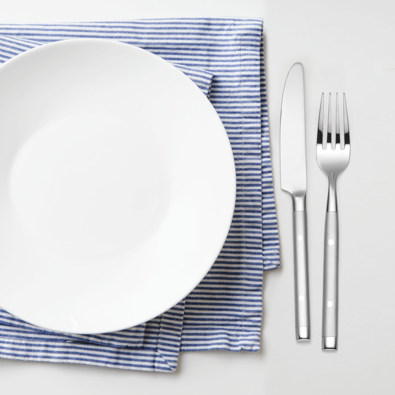 Hampton Forge Hampton Signature Shangrila 20-piece flatware set for four, including forks, knives, spoons, and teaspoons arranged on a table.