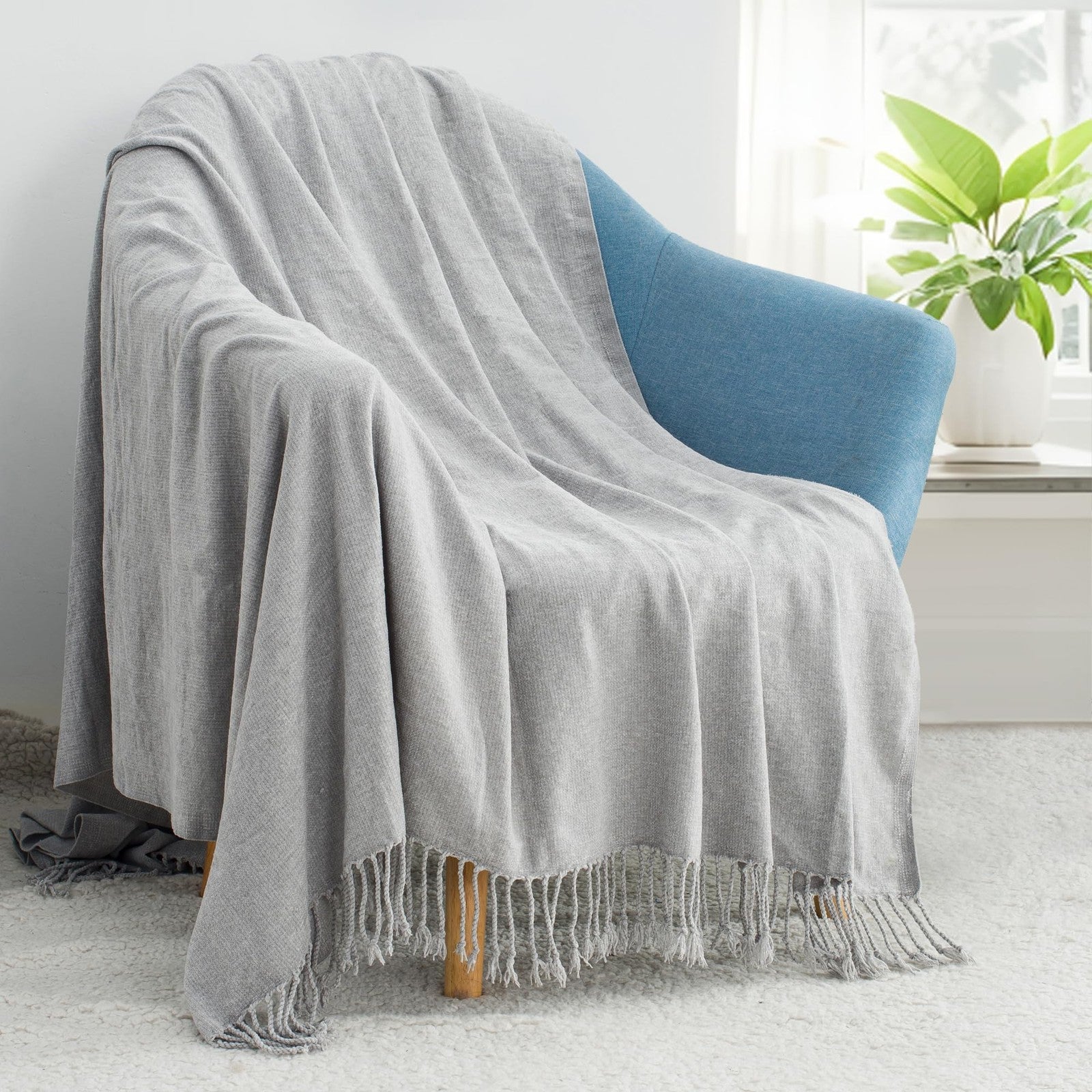 GINAMUSE chenille throw blanket with tassels draped over a couch, showcasing its soft lightweight texture and cozy design.
