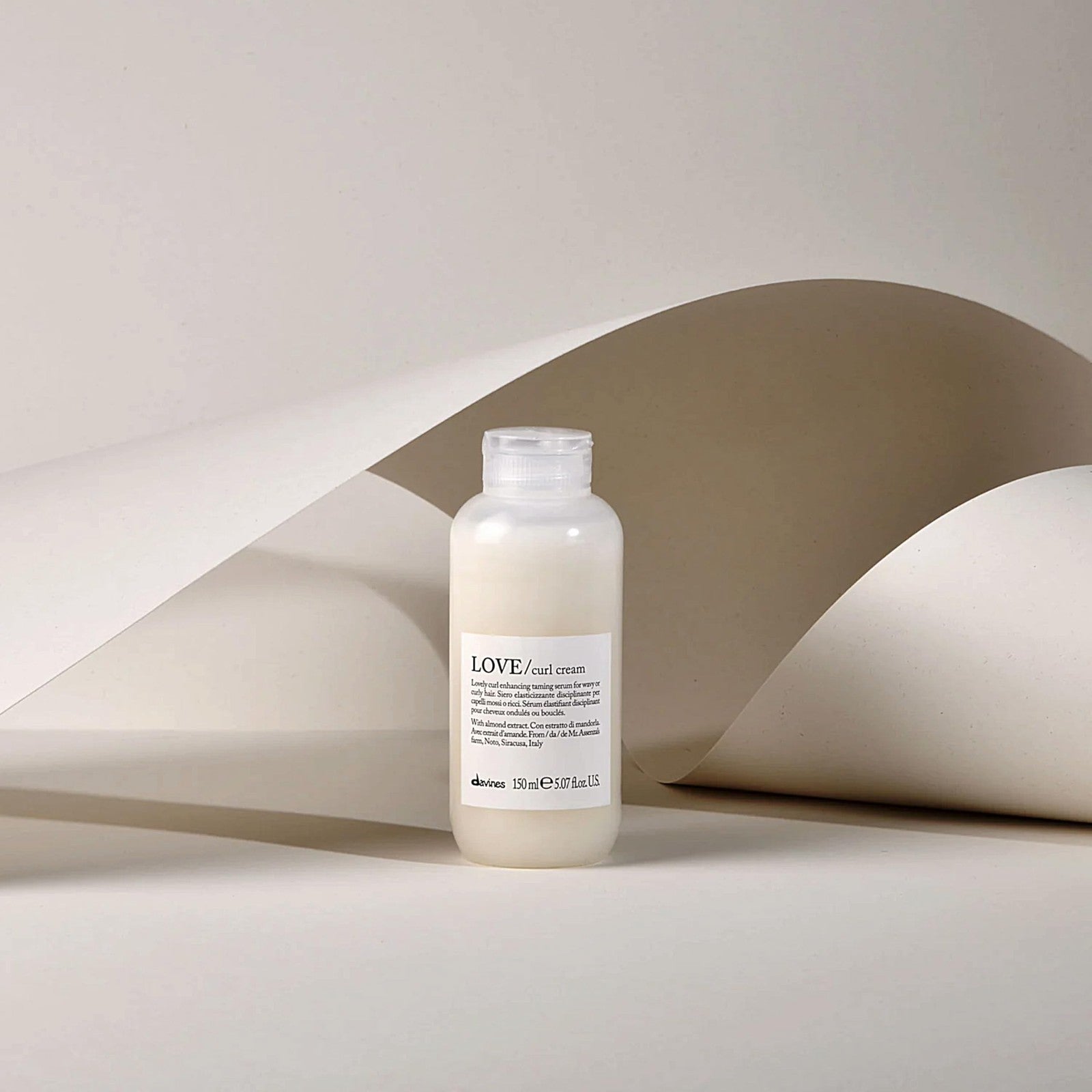 Davines LOVE Curl Cream weightless curl defining serum for curly hair, shown in a sleek tube with a pump dispenser.