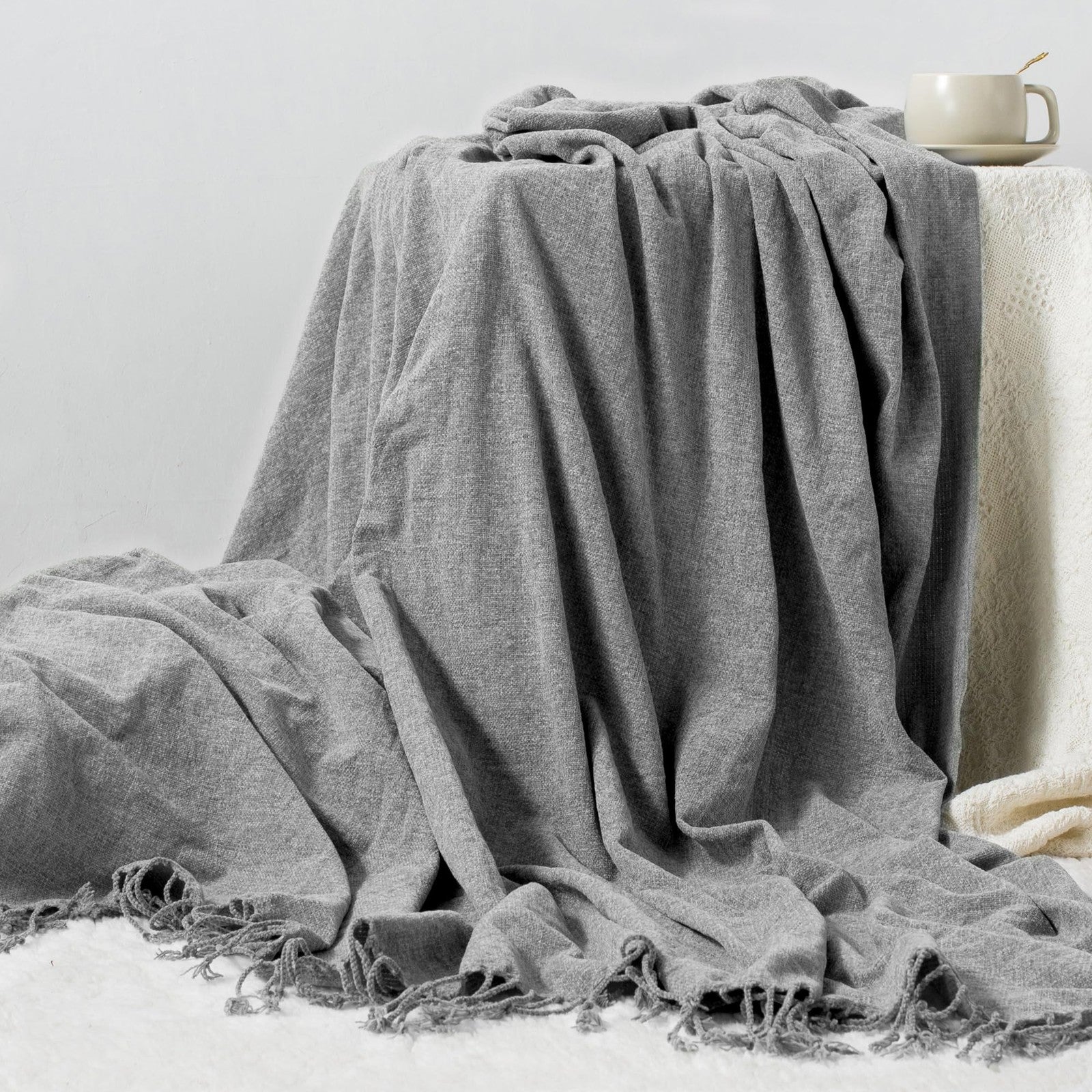 GINAMUSE chenille throw blanket with tassels, 60x88 inches, soft lightweight fabric draped over a cozy couch.