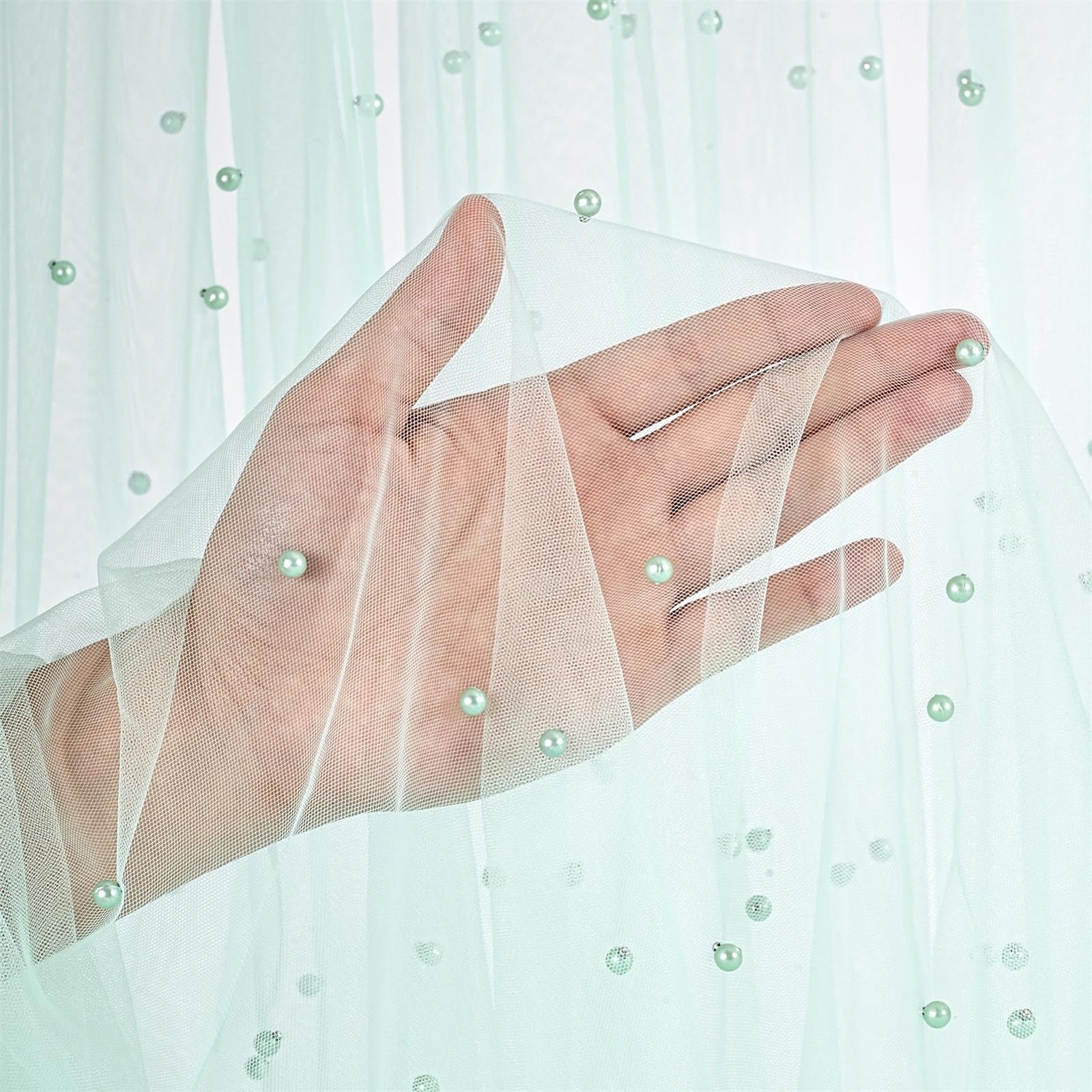 Light green pearl tulle fabric by B-COOL, sheer mesh material ideal for sewing and craft projects, shown in a 10-yard roll.