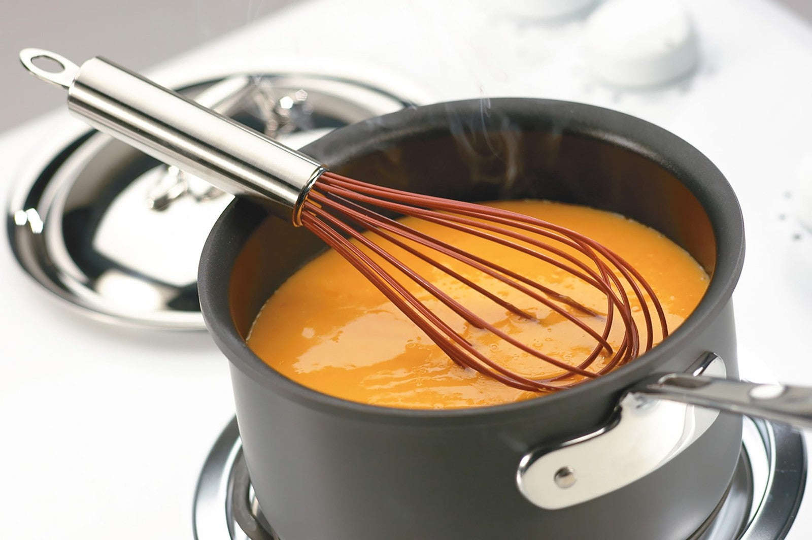 Cuisipro 10-inch red silicone piano whisk with ergonomic handle, ideal for mixing and whisking in kitchen cookware.