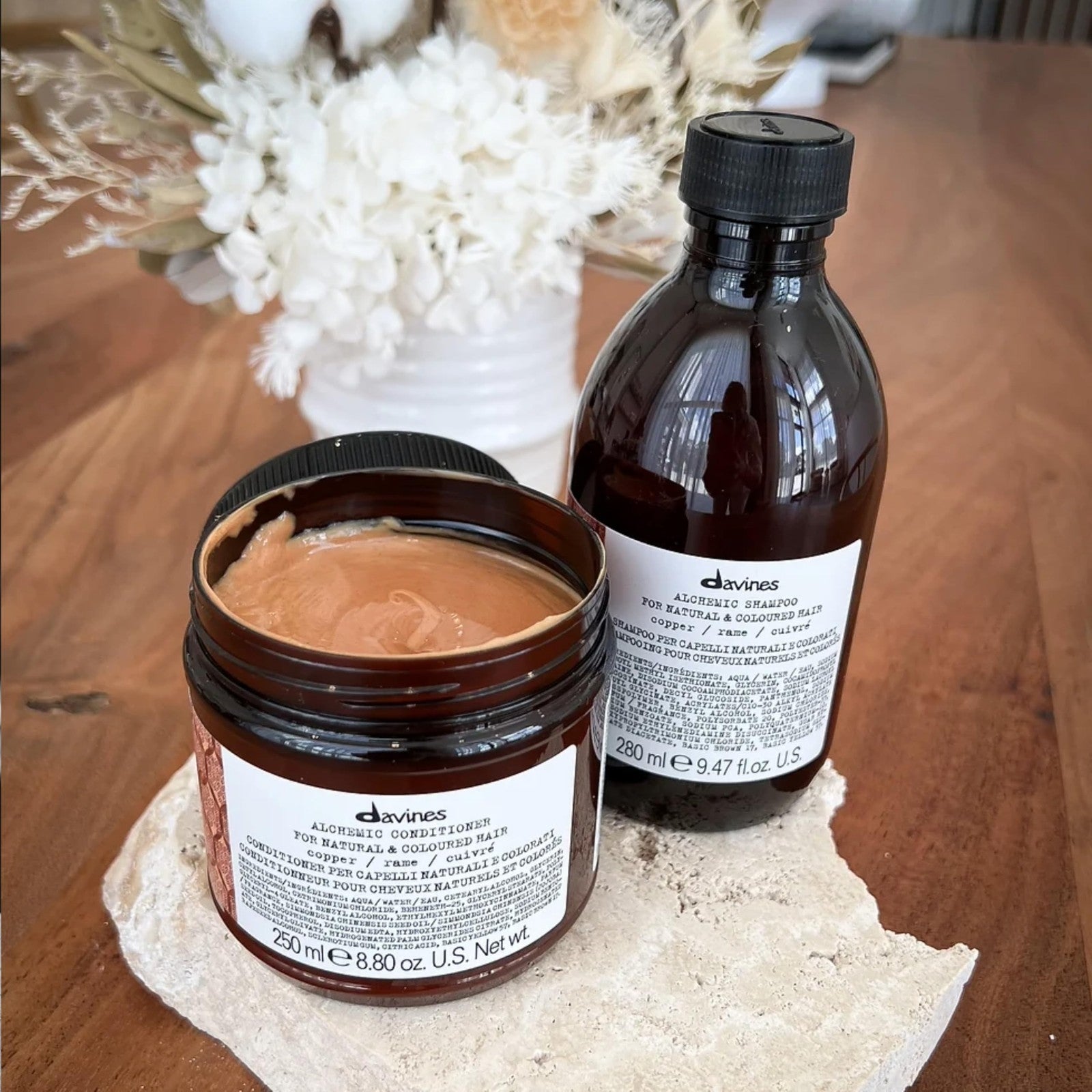 Davines Alchemic Copper Conditioner bottle with black cap and orange label, 8.81 oz, on a white background.
