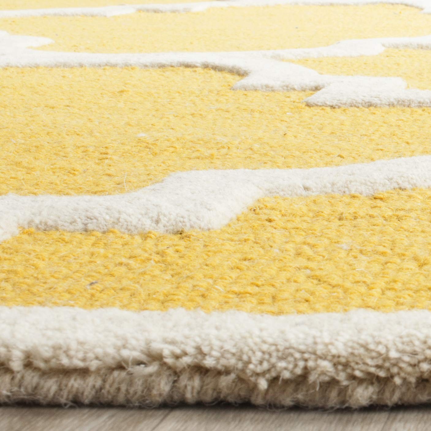 Safavieh Cambridge Collection 6x9 handmade Moroccan rug with gold and ivory geometric patterns on a wooden floor.