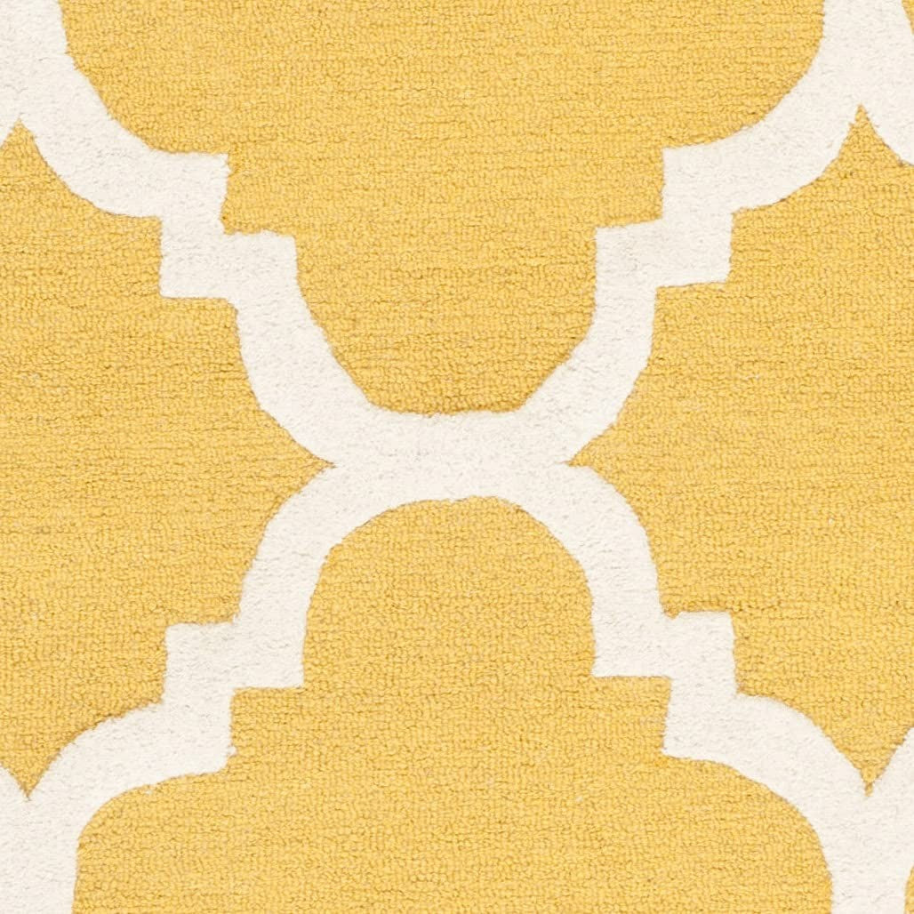 Safavieh Cambridge Collection 6x9 handmade Moroccan rug with gold and ivory geometric patterns on a soft textile background.