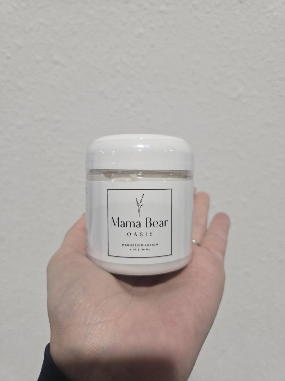 Mama Bear Oasis magnesium cream with arnica and lavender, a soothing skin moisturizer in a white jar.