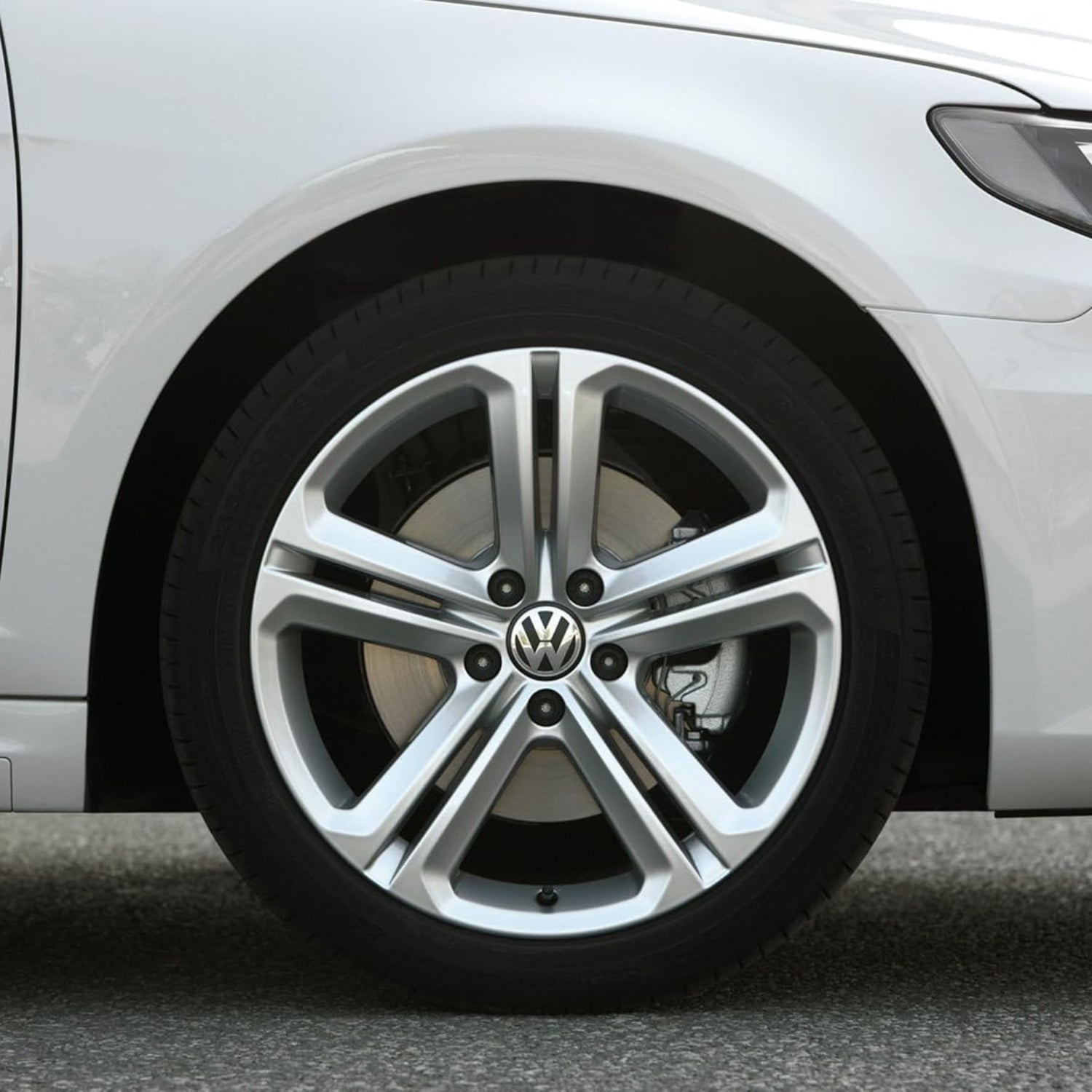 Volkswagen center cap with VW logo, unbranded wheel hub cover, round design, metallic finish, on a neutral background.