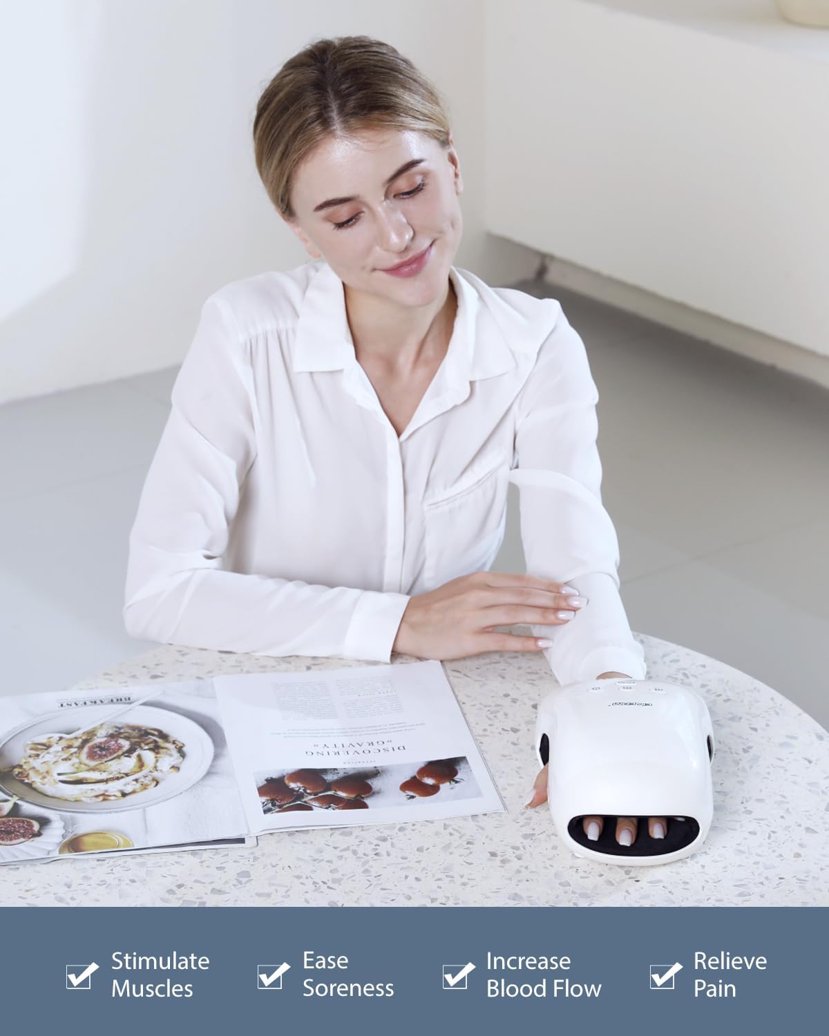 Woman using a white handheld device on her arm with a magazine on the table.