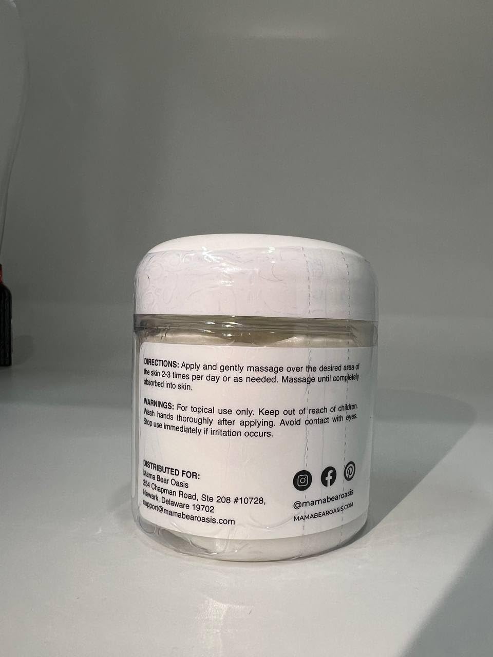 Mama Bear Oasis Magnesium Cream skin moisturizer with arnica and lavender, shown in a jar with fresh lavender and arnica flowers.
