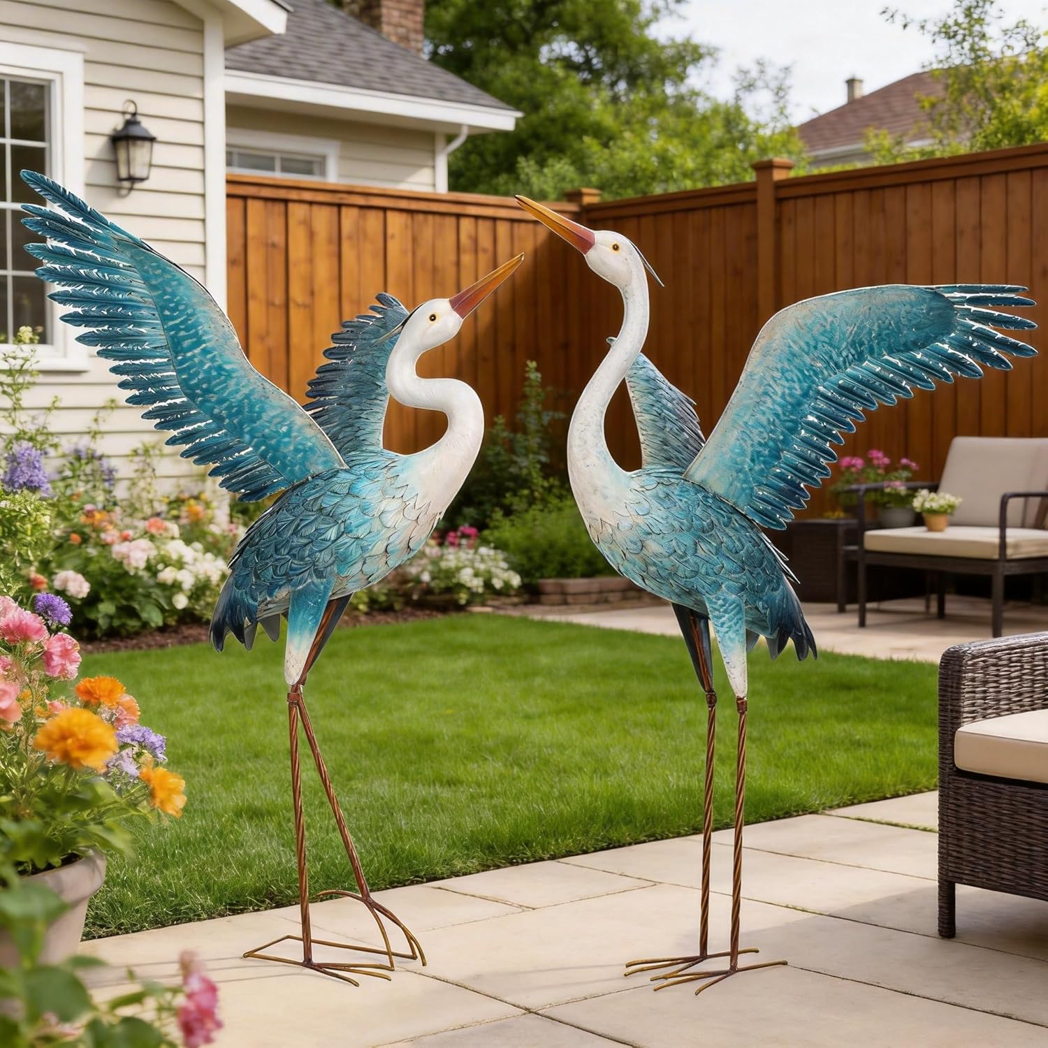 Two white and blue metal heron crane garden statues from chisheen, outdoor yard art sculpture, detailed bird figures.
