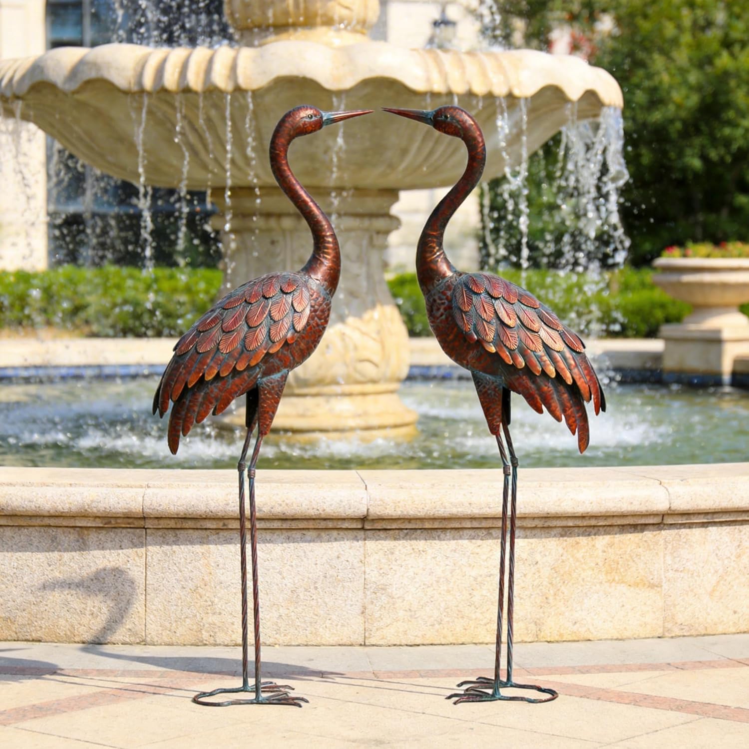 Two metal garden crane statues by Chisheen, outdoor yard art sculptures with detailed crane figures in a natural setting.