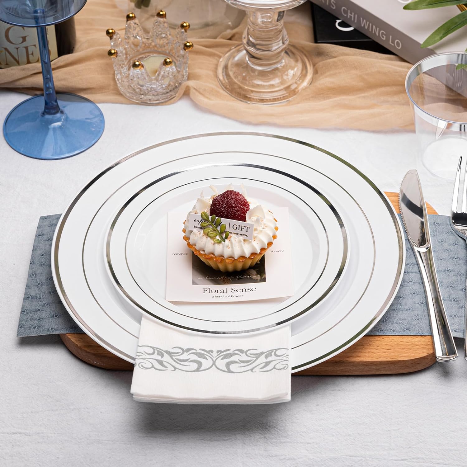 N9R 700-piece silver disposable dinnerware set with white plastic plates, cups, and utensils for 100 guests.