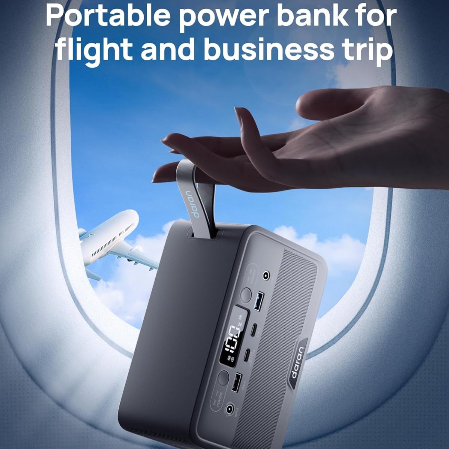 Portable power bank held by a hand with airplane and sky background
